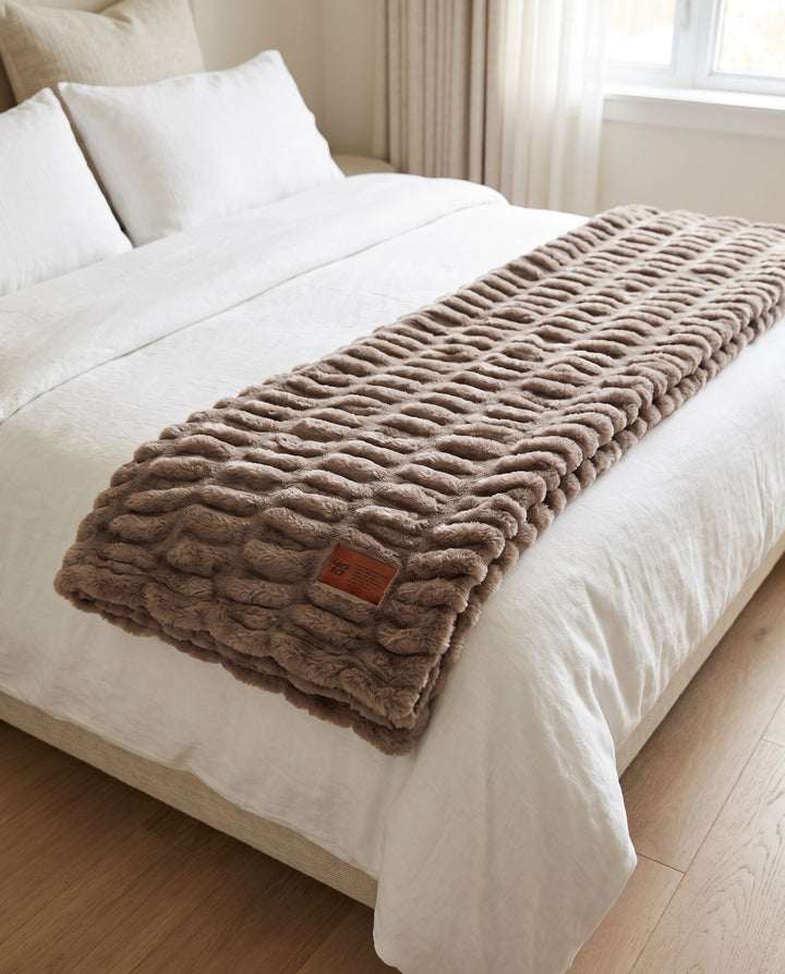 Be Still Blanket folded across the foot of a white bed