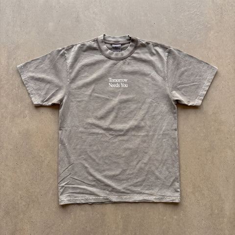 Cement Tomorrow Needs You tee flat lay on neutral background