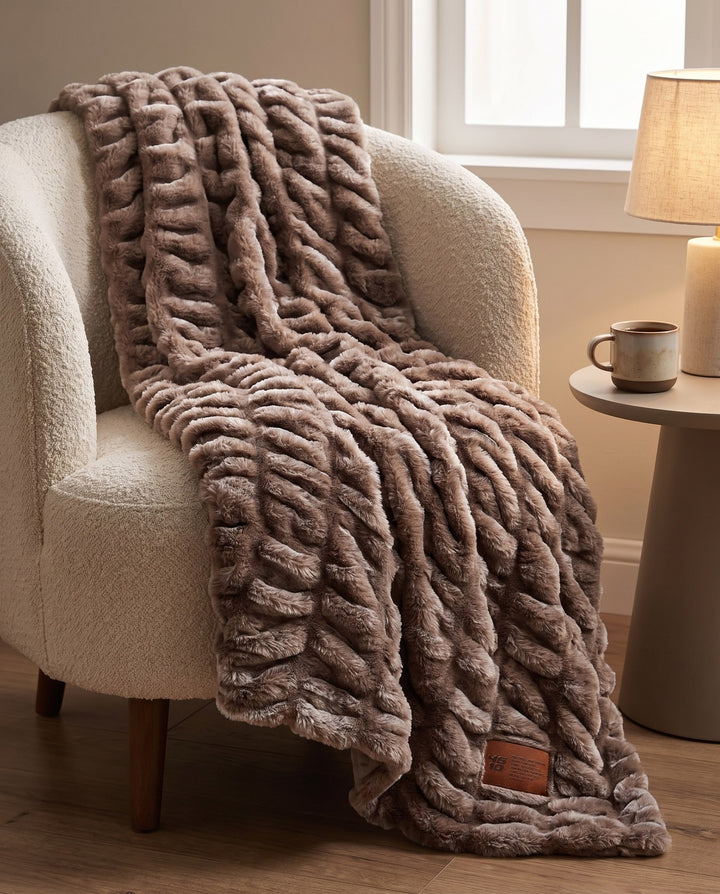 Be Still Blanket draped over a cream boucle armchair