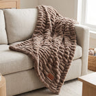 Be Still Cozy Throw Blanket in mocha faux fur draped across a linen sofa, with its leather Psalm 46:10 patch
