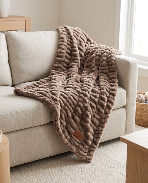 Be Still Cozy Throw Blanket in mocha faux fur draped across a linen sofa, with its leather Psalm 46:10 patch