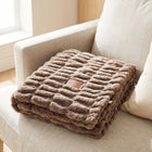 Be Still Blanket folded on a sofa, showing the debossed leather patch with the 46/10 logo and Psalm 46:10
