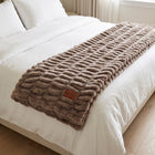 Be Still Blanket folded across the foot of a white bed