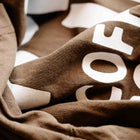 Close-up of brown oversized tee with bold white coffee-themed text print