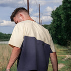Man outdoors wearing two-tone beige and navy streetwear tee with short sleeves