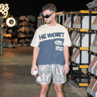 Man wearing 'He Won't Give Up On Me' Christian streetwear t-shirt and camo shorts indoors