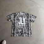 Gray camo t-shirt with bold JLY Jesus Loves You text, laid flat on concrete floor