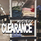 Folded blank hoodies and t-shirts stacked on shelves, text overlay reads Mystery Clearance.