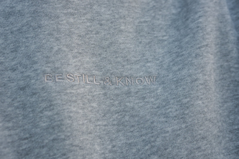 BE STILL AND KNOW embroidered tone on tone on the Heather Gray hoodie
